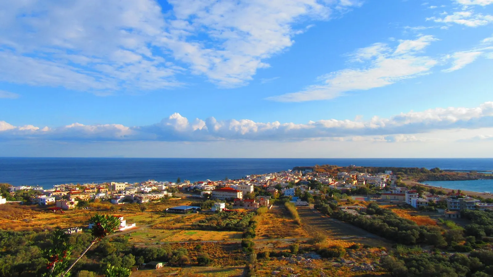 Ciel bleu et nuages au-dessus d'un village côtier de Crète et de la mer