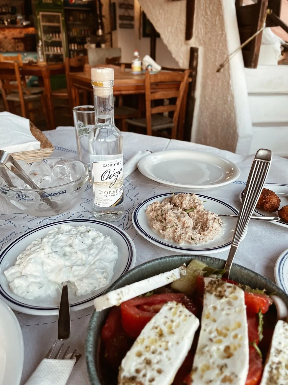 Une table de mezze à partager dans une taverne grecque, avec salade, dips et pain