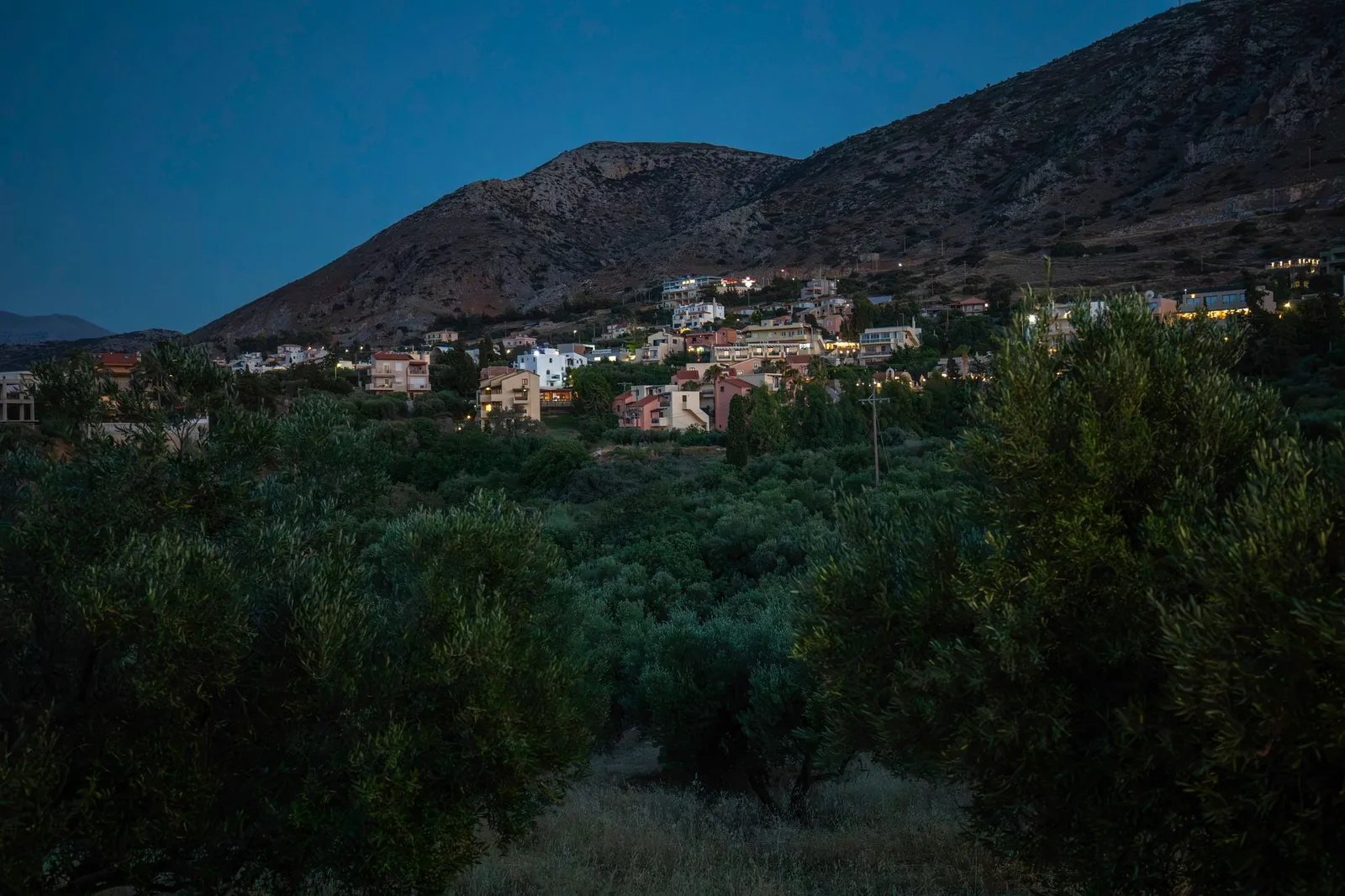 Village de montagne entouré d'oliviers au crépuscule, au pied d'un massif crétois